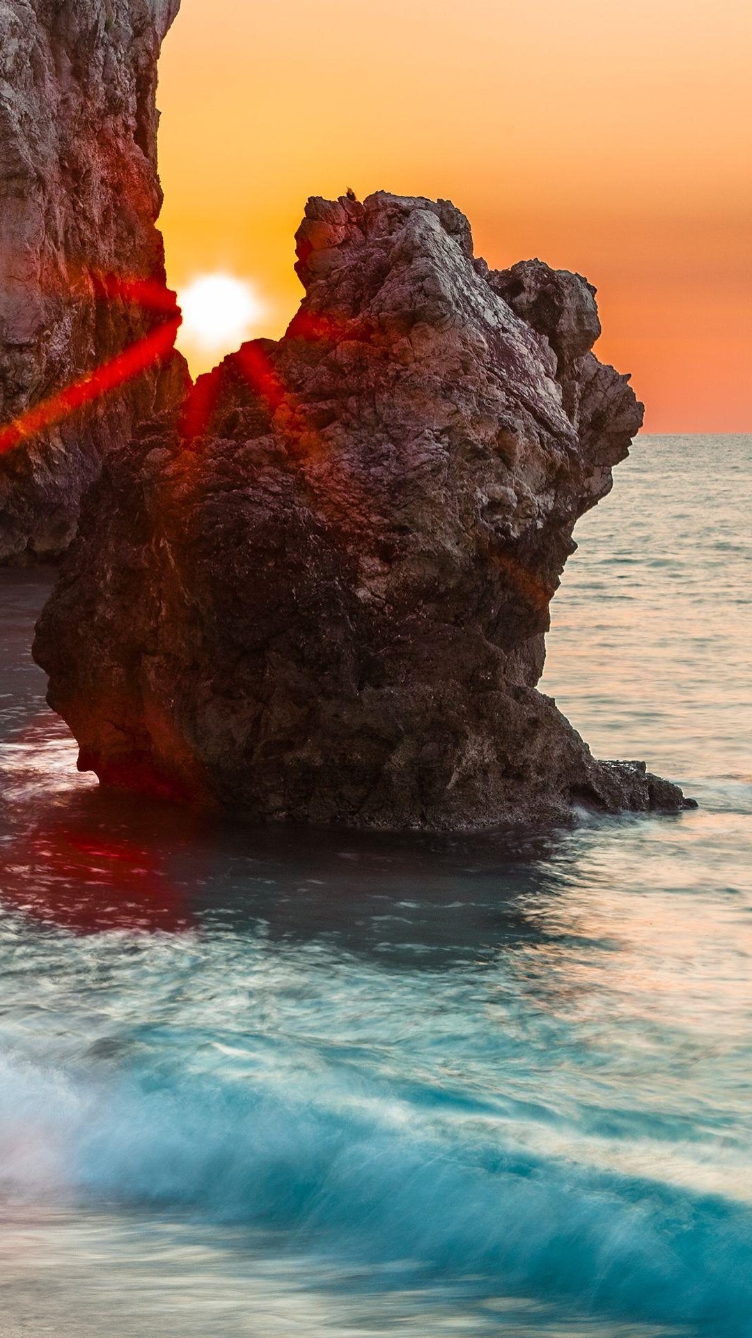 海滩岩石缝中的闪耀日出